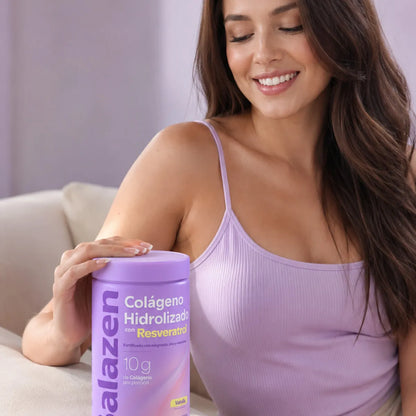 Mujer sonriente y feliz sosteniendo un envase de Colágeno Hidrolizado Balazen con Resveratrol Vainilla en un sofá.